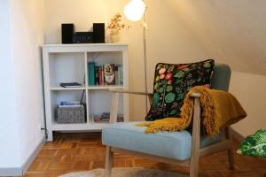 a room with a chair with a pillow and a book shelf at Ferienwohnung-Familie-Baasch in Embsen