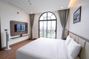 ein Schlafzimmer mit einem großen Bett und einem Fenster in der Unterkunft Sun Hotel Sam Son in Sầm Sơn
