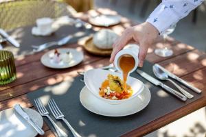 a person holding a cup of coffee and a bowl of food at Moselromantik Hotel Kessler Meyer - Adults Only in Cochem