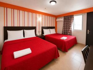 ein Hotelzimmer mit zwei Betten mit roter Bettwäsche in der Unterkunft Hotel ROLOVI in Veracruz