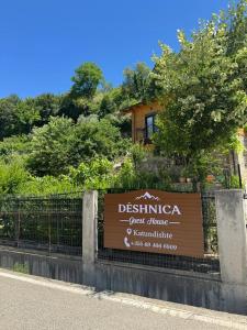 a sign for a guest house in front of a fence at Guesthouse Deshnica in Këlcyrë