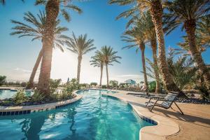 a pool with palm trees and a chair in a resort at Sand Swept in Galveston