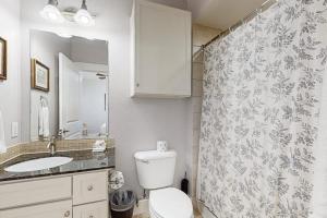 a bathroom with a toilet and a shower curtain at Sand Swept in Galveston +30 photos