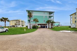a large green building with palm trees in front of it at Sand Swept in Galveston