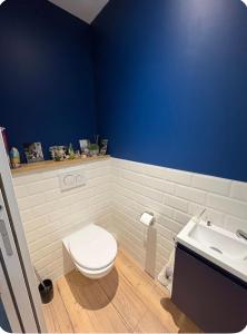 a bathroom with a white toilet and a blue wall at Chambre du petit bois in Montceaux