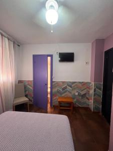 a room with a bed and a blue door and a tv at Pensión El Alamo in Lepe