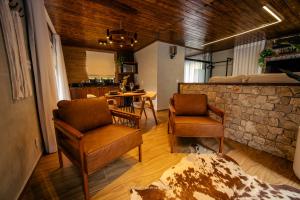 a living room with two chairs and a stone wall at Hotel Fazenda Gabro - Vitra in Apiaí