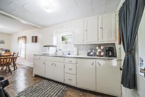 a kitchen with white cabinets and a dining room at The Wrens Nest in Baltic