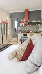 a bedroom with a bed with pillows and a kitchen at Knysna Holiday Cottage in Knysna