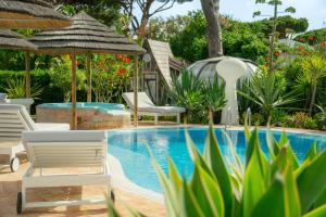 a resort pool with chairs and umbrellas and plants at Villa CHELSEA in Vilamoura