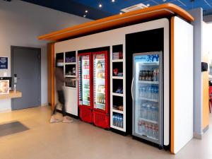 a woman is walking past two refrigerators in a store at ibis budget Leme SP in Leme