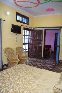 a bedroom with a bed with chairs and a television at Devki Homestay in Kanatal