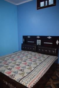 a bed with a quilt on it in a room at Devki Homestay in Kanatal