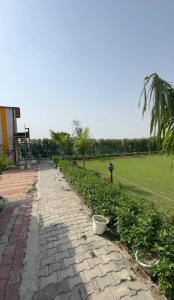 a brick path leading to a park with a field at Aradiya Farm House in Noida +3 photos