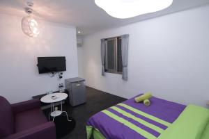 恆春的住宿－ZL民宿，一间卧室配有一张紫色的床和一张沙发