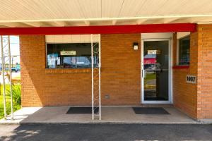 a red brick building with a glass entry door at Pen Ann by Capital O Pharr-McAllen TX in Pharr +16 photos