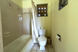 a bathroom with a toilet and a tub and a window at Pen Ann by Capital O Pharr-McAllen TX in Pharr