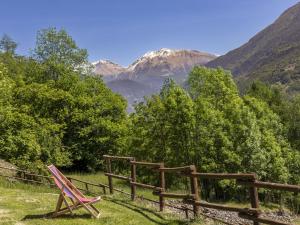 a chair sitting in the grass near a fence at Chalet Chalet Anna by Interhome in Grosotto