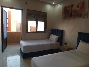 a hotel room with two beds and a window at Riad Bollywood Spacious 5 Beds Stay in Benguerir