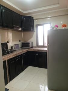 a kitchen with black cabinets and a stainless steel refrigerator at Riad Bollywood Spacious 5 Beds Stay in Benguerir