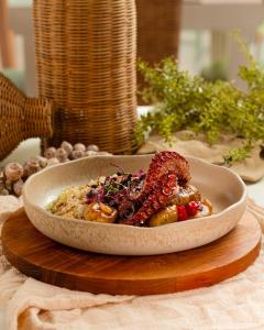 a bowl of food sitting on a wooden table at Pousada Pedra da Ilha in Penha +30 photos