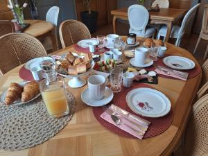 a wooden table with breakfast foods and orange juice at Chambre d'hotes Les Rives de la Tronne in Mer