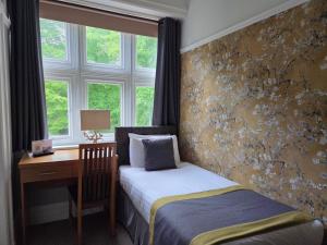 a bedroom with a bed and a desk and window at Sawrey House in Near Sawrey