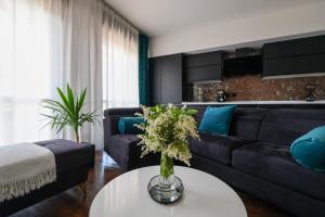 a living room with a couch and a table with flowers at Blu Petrolio Stay-Karabas Apartments-parcheggio in Vicenza