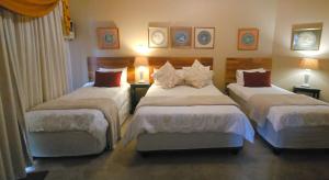a hotel room with three beds and two lamps at Rest-a-While Guest House - Pretoria in Pretoria +18 photos