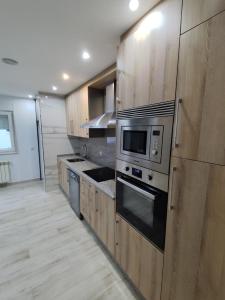 a large kitchen with wooden cabinets and a microwave at Luz De Luna in Negreira