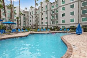 a pool with chairs and umbrellas in front of a building at Hawthorn Suites Suite Near Universal & I-Drive in Orlando