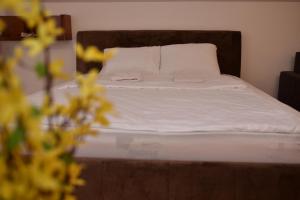 a bed with white sheets and a wooden head board at SIBE Apartments in Banja Luka +7 photos