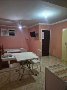 a room with two beds and a table and chairs at Pousada Alto Riviera in Macaé +10 photos