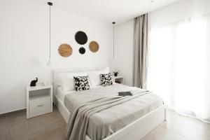 a white bedroom with a bed and a window at Blue Cyclades Villas in Kastraki