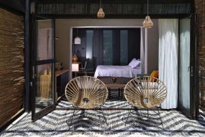 a bedroom with two chairs and a table and a bed at Ekies All Senses Resort, a Member of Design Hotels in Vourvourou