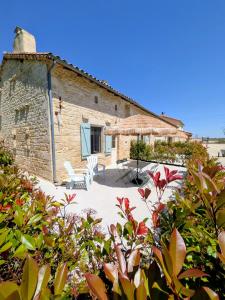 a stone house with a patio in front of it at Gîtes climatisés classés 4 étoiles Au Petit Bonheur de Lorigné in Lorigné