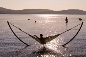 a man laying in a hammock in the water at Ekies All Senses Resort, a Member of Design Hotels in Vourvourou