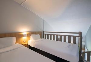 two beds in a small room with white sheets at B&B HOTEL Beauvais in Beauvais