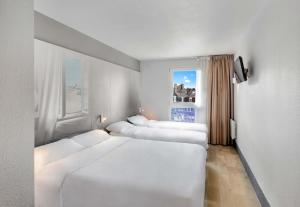a row of beds in a room with a window at B&B HOTEL Dunkerque Centre Gare in Dunkerque