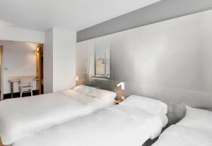 two beds in a room with white walls at B&B HOTEL Dunkerque Centre Gare in Dunkerque