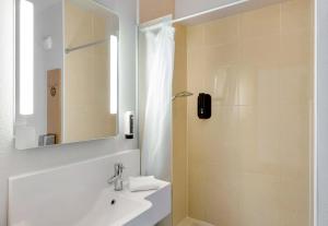 a bathroom with a sink and a shower with a mirror at B&B HOTEL Dunkerque Centre Gare in Dunkerque +31 photos