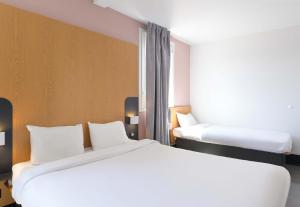 a hotel room with two beds and a window at B&B HOTEL Lieusaint Carré Sénart in Lieusaint