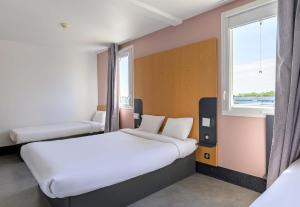 a hotel room with two beds and a window at B&B HOTEL Lieusaint Carré Sénart in Lieusaint