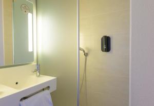 a bathroom with a shower and a sink and a mirror at B&B HOTEL Lieusaint Carré Sénart in Lieusaint