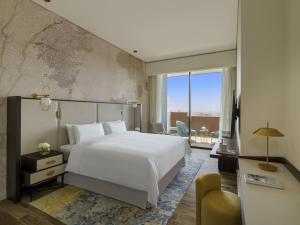 a bedroom with a white bed and a large window at Fairmont Ramla Riyadh in Riyadh