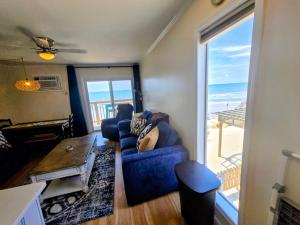 a living room with a blue couch and a view of the beach at Steps to the Ocean! 219 in North Topsail Beach