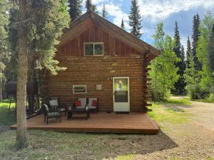 a log cabin with a deck with furniture in front at Little Dry Cabin #3 in Fairbanks