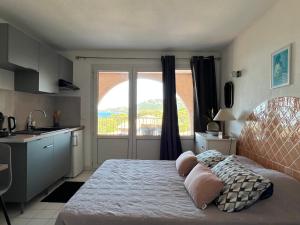a bedroom with a bed and a kitchen with a window at Résidence les pieds dans l'eau in Porto-Vecchio