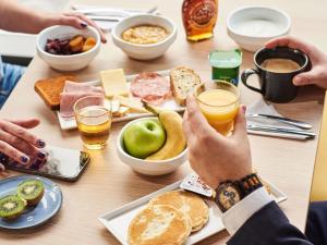 a person holding a glass of orange juice at a table with food at ibis Bethune Centre Gare in Béthune