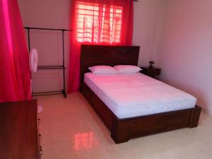 a bedroom with a large bed with red curtains at Complexe La Belle Rosie in Les Cayes